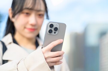 オフィス街でスマホを使用する日本人ビジネスウーマン
