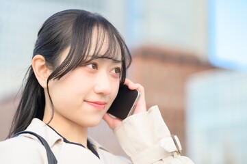 オフィス街でスマホを使用する日本人ビジネスウーマン