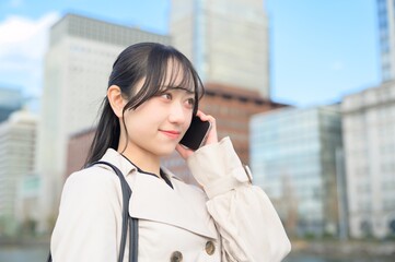 オフィス街でスマホを使用する日本人ビジネスウーマン