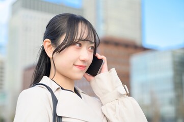 オフィス街でスマホを使用する日本人ビジネスウーマン