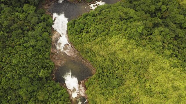Top-down aerial view of Seo My Ty Waterfall flowing through dense green forest in Sa Pa, Vietnam. Remote mountain landscape with cascading freshwater, lush vegetation and natural scenery.