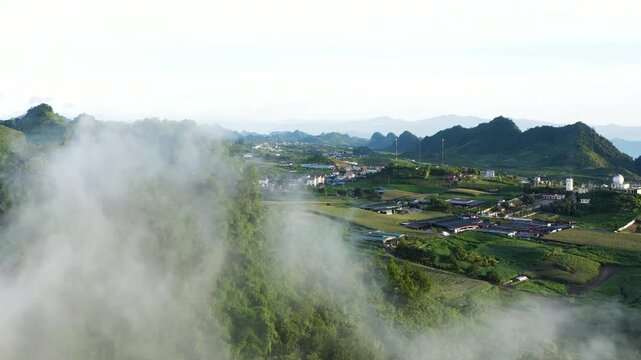 Moc Chau, Vietnam mountain valley covered in sunrise fog with green hills, rural village and morning light, peaceful nature and scenic landscape.