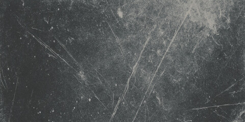 A grayscale image depicts a dark textured surface with scattered light streaks and subtle imperfections throughout