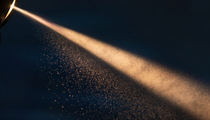 Fine particles illuminated by light streaming through a dark background.