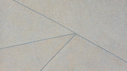 The walkway surface is made of exposed aggregate concrete with beige, gray, and light brown stones. The rough natural texture features straight gray grout lines forming an abstract geometric pattern.