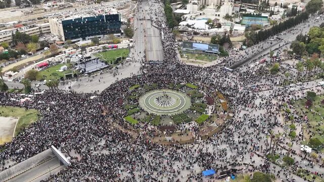 An aerial view of thousands of Syrians celebrating the end of the war in Damascus, carrying Syrian flags.