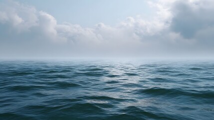 Fototapeta premium A serene hazy ocean expanse under a cloudy sky with gentle waves