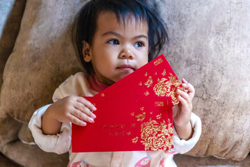 Cute baby holding a red ang pao envelope with gold details, symbolizing luck, blessings, and prosperity during Lunar New Year or Chinese New Year