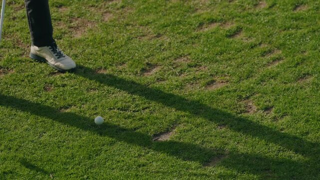 Close view of golfer striking ball with putter on green