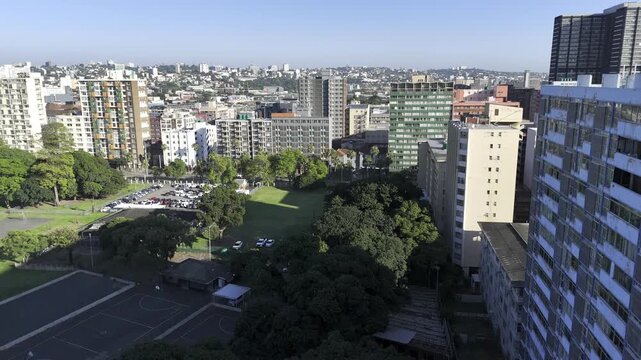 Drone rises in shade of building over Albert Park, while drone faces north in the early morning on the southeast side of downtown Durban, South Africa