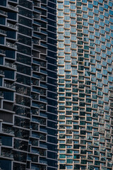 Fototapeta premium two skyscrapers with geometric glass facade and strong shadow line. Urban architecture and abstract pattern for business or cityscape background.