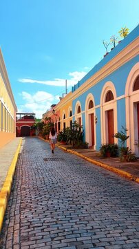 Woman walks by the cobbled road along the colorful buildings. Stroll by the cozy streets of La Perla, Puerto Rico. Vertical video.