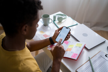 Man planning schedule at desk with smartphone and planner