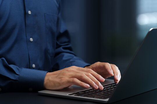 Businessperson using laptop computer at desk in office. Closeup of hands and keyboard. Business technologies.