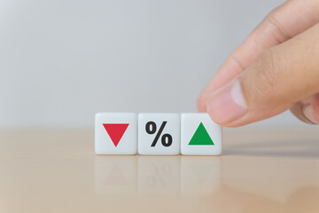Hand arranging dice with down arrow, percent sign, and up arrow, symbolizing financial adjustment, market analysis, interest rate change, price comparison, and economic strategy