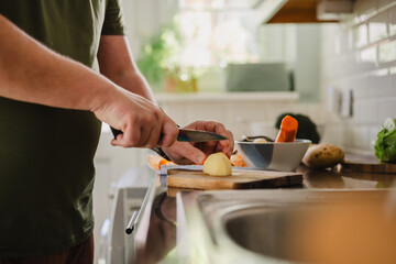 Hand peeling vegetable for vegan soup preparation in kitchen