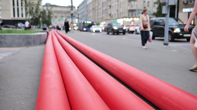 Red utility pipes lying on city street during urban infrastructure construction