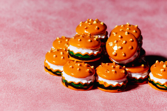 Miniature burger toys with glossy orange buns on pink background