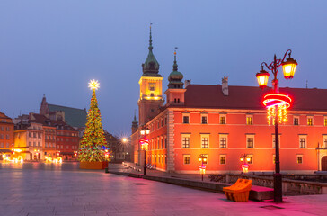 Christmas tree and historic building with festive lights in Warsaw Poland during winter evening