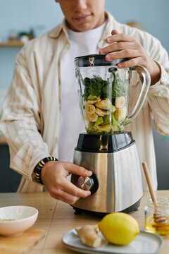 Teenager preparing a healthy smoothie with a blender in the kitchen