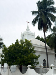 White facade of Zion Church with a cross atop and palm trees in Tharangambadi, Tamil Nadu, a historic Danish colonial-era Protestant church.