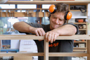 Carpenter working precisely on wooden furniture in workshop