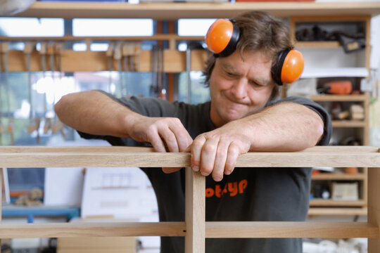 Carpenter working precisely on wooden furniture in workshop