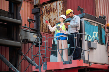 Workers inspecting containers at a cargo port, one pointing and discussing, highlighting logistics and transportation