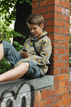 Teenager in star-pattern hoodie using mobile phone outdoors in Berlin