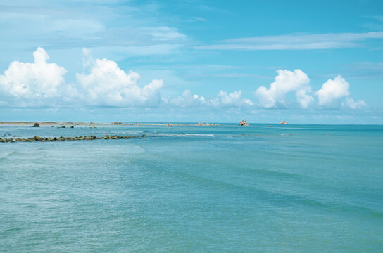 Clear turquoise water scene with distant horizon and fluffy clouds floating above the sea, Kuala Penyu, Sabah, Malaysia.