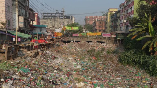 Polluted river full of plastic trash flowing under bridge in Dhaka