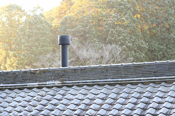 瓦屋根に伸びる薪ストーブの煙突