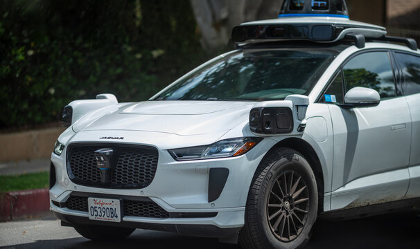 LOS ANGELES, CA - May 12, 2025: Waymo self driving taxi cab driving on city street, closeup.