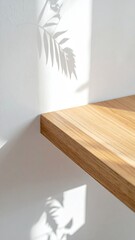 Clean wood shelf with plant shadow on white wall