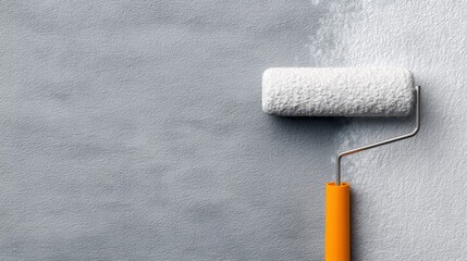 A paint roller rests against a textured grey wall, showcasing a fresh coat of paint in progress, highlighting home improvement and renovation themes.