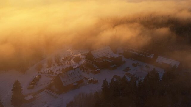 Kralovka lookout tower stands tall in the Jizera Mountains. Clouds cover the area as winter scenes unfold. Visitors explore the landscape and enjoy the views.