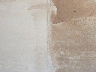 Interior wall showing contrast between wet and dry plaster surfaces, illustrating the drying process and different stages of renovation work.
