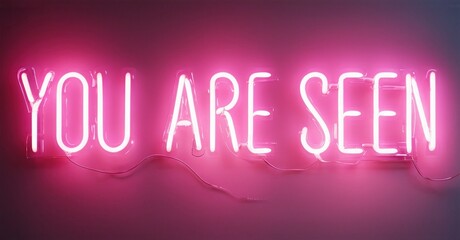 Fototapeta premium Bright pink neon sign displays words YOU ARE SEEN against dark magenta background. Simple message, positive affirmation.