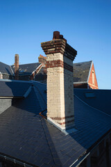 Chemin&eacute;e en briques sur le toit en ardoise d'une maison