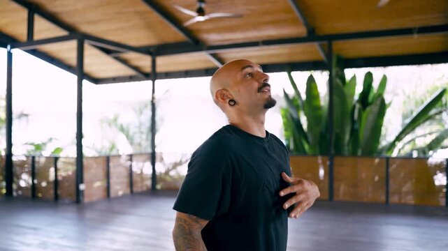 Male pole dance instructor with tattoos and ear plugs coaching a female student. Personal trainer assisting an athletic woman during her lesson