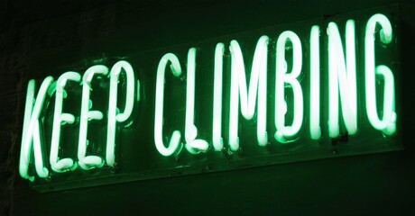 Bright green neon sign displays motivational phrase. Dark background emphasizes glowing text, creating dramatic effect. Simple, inspiring message.