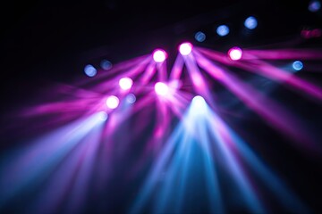 Soft focus image of stage lighting with purple and blue beams against a dark backdrop