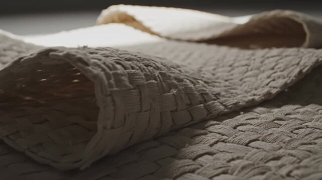 Woven cotton mat and rolled braided rug soft natural light creating cozy textured layers and warm relaxed mood woven cotton placemat with textured basket weave pattern neutral beige tones softly lit