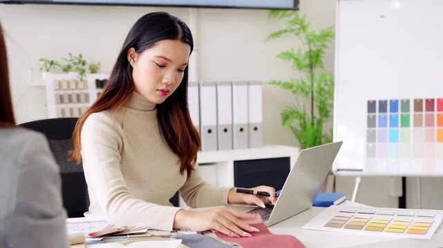 Young asian female interior designer or architect working on creative project with drawing, material sample , laptop computer in office. Business of Real estate, home decoration , renovation concept.