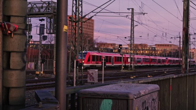 Train is captured in motion as it crosses the Rhine in the Hohenzollern Bridge, looking east toward the district of Deutz during a vibrant sunset.
