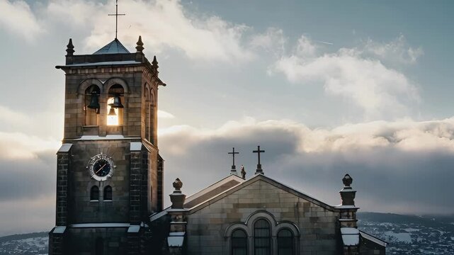 Sunlight shining through a historic church bell tower at sunset on a cold winter day. Majestic stone cathedral with a clock and cross against a cloudy sky. Cinematic panoramic banner