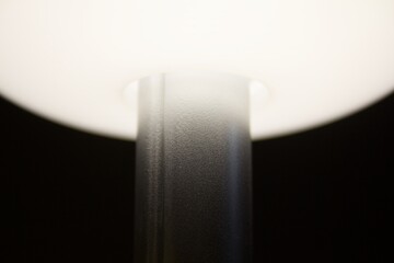 Close-up of a modern minimalist lamp with soft glowing light and metallic texture