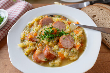 Traditional german savoy potato stew with sausage on plate und rustic background
