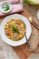 Traditional german savoy potato stew with sausage on plate und rustic background