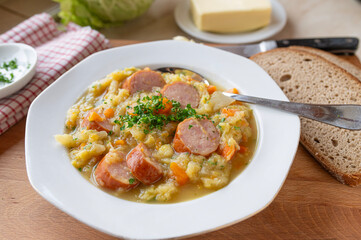 Traditional german savoy potato stew with sausage on plate und rustic background